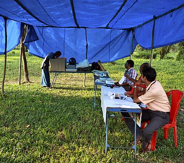 A man (Left) casts his vote at a temporary polling booth on Ramanthuruthu Island during the state assembly election