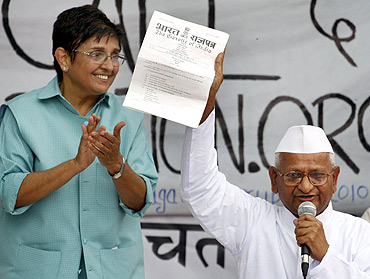 Hazare displays a note from the Indian government to his supporters as former Indian police officer and social worker Kiran Bedi watches