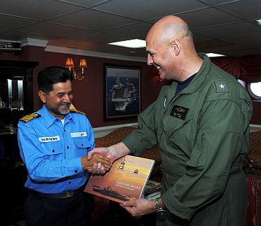 Capt Thom Burke, commanding officer of the aircraft carrier USS Ronald Reagan (CVN 76), exchanges a gift with Indian navy Rear Adm. Harish Bisht, flag officer of Commanding Eastern Fleet in the captain's in-port cabin aboard Ronald Reagan