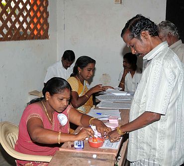A lady poling officer administering indelible ink to the finger of a voter at a polling booth at Kanyakumari