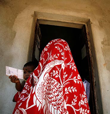 A child holds the voting card of his mother as she goes to a polling booth