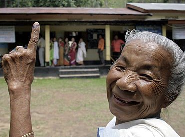 A woman shows her ink-marked finger after casting her vote at a polling station