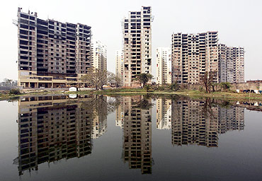 Residential apartments under construction are reflected on the surface of a pond in Kolkata