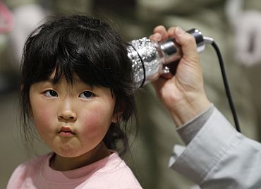 A four-year-old girl is tested for possible nuclear radiation at an evacuation centre in Koriyama, Fukushima Prefecture
