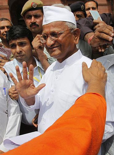 Social activist Anna Hazare gestures to photographers after attending a joint Lokpal panel meeting in New Delhi