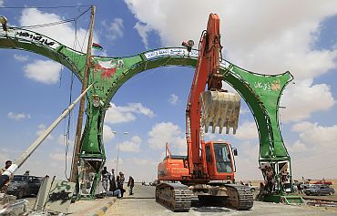 An excavator travels past the western entrance gate at the front line along the western entrance in Ajdabiyah