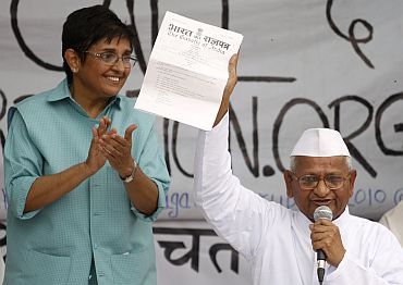 Anna Hazare displays a note from the government to his supporters as Kiran Bedi watches in New Delhi