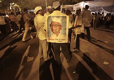 A supporter wearing a paper poster of social activist Hazare attends a protest against corruption in New Delhi