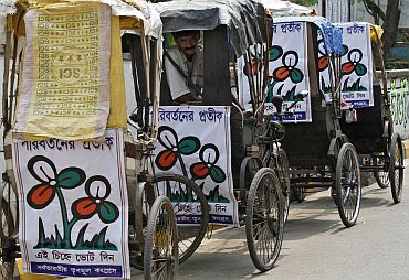 A man sits in a cycle rickshaw decorated with Trinamool Congress placards on a roadside in Kolkata