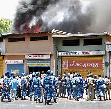 Riot police watch as smoke rises from shops in Ahmedabad during the 2002 riots