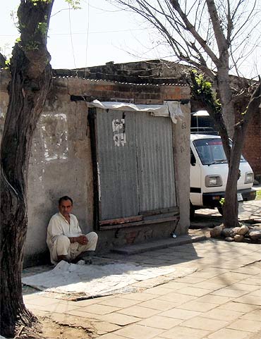 A man sits by a shop at a camp for Kashmiri migrants in Jammu