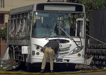 A security official examines a bus carrying Pakistani navy officials after it was damaged by a bomb in Karachi on Tuesday