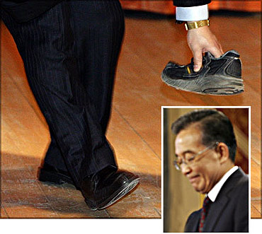 A security guard picks up a shoe that was thrown towards Chinese Premier Wen Jiabao (inset) at the University of Cambridge.