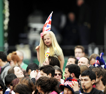 A girl with a British flag smiles among people gathered outside Buckingham Palace before the wedding of Britain's Prince William and Kate Middleton at Westminister Abbey.