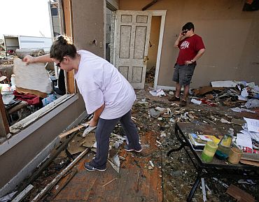 Ashla Sullivan throws out debris from her destroyed house as her husband, Adam Sullivan, talks on the phone