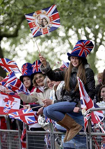 A royal supporter waves a Union Jack as she waits along the Procession Route in London