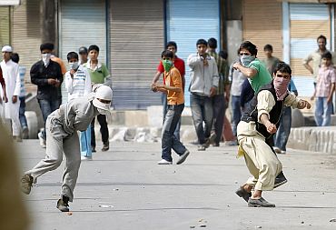 Kashmiri protestors throw stones towards security personnel during an agitation in Srinagar