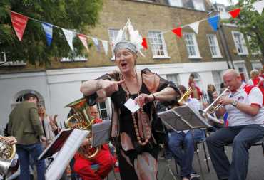 Resident and former opera singer Dame Ann Evans sings as the brass band plays Rule Britannia during a street party to celebrate the royal wedding