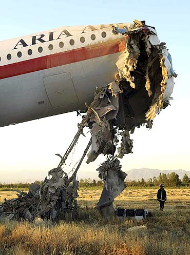 An official stands beside the wreckage of a passenger airplane in Mashhad, Iran, on July 24, 2009. 17 were killed when the aircraft caught fire while landing at the airport of Mashhad