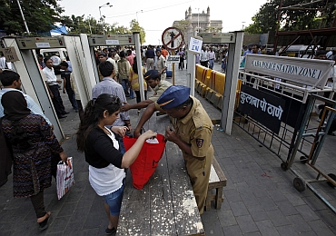 A policeman checks a visitor's bag at a security checkpoint at the entrance of the Gateway of India