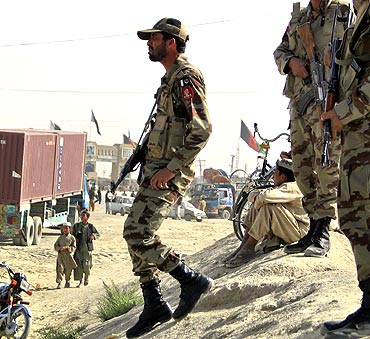 Paramilitary soldiers stand guard along a road near the Afghanistan border