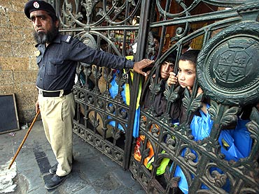 Children watch an anti-America rally from behind the closed gate of a market in Karachi