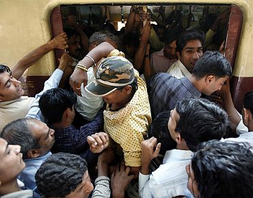 Commuters make their way into a crowded compartment of a suburban train in Mumbai
