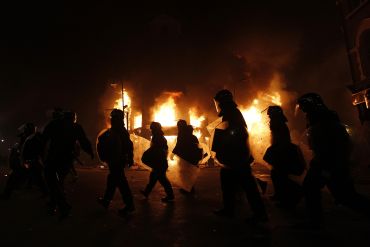 Police officers wearing riot gear walk past a burning building in Tottenham, north London.