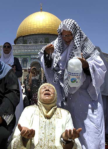 A Muslim woman tries to cool down with water in front of the Dome of the Rock on the compound known to Muslims as al-Haram al-Sharif and to Jews as Temple Mount in Jerusalem's Old City