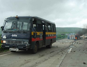 A police van forms a cordon around a vehicle set ablaze by protestors