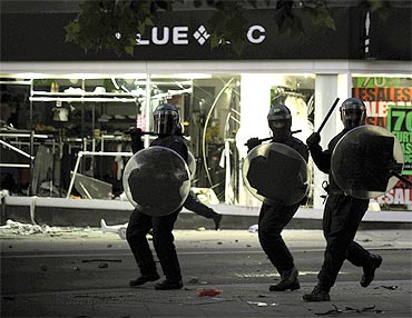 Riot police charge past a looted shop on Peckham High Street in south London on Monday night.