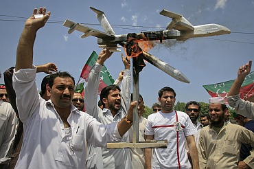 Activists of PTI hold up a burning mock drone aircraft during a rally against drone attacks in Peshawar