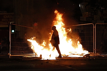 A rioter walks through a burning barricade in Liverpool
