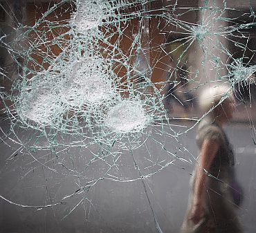A woman walks past a broken cafe window