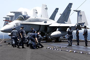 US Navy personnel work in front of a F/A-18 Hornet fighter jet on the flight deck of the aircraft carrier USS Carl Vinson anchored off the Manila bay, where Osama bin Laden was given burial ritual