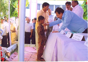 State government official hands over a beneficiary cheque to a child from the Mahadalit community