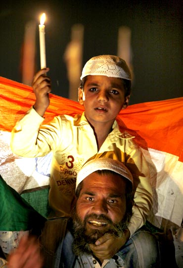 A supporter of social activist Anna Hazare and his child attend a candlelight campaign against corruption at India Gate in New Delhi