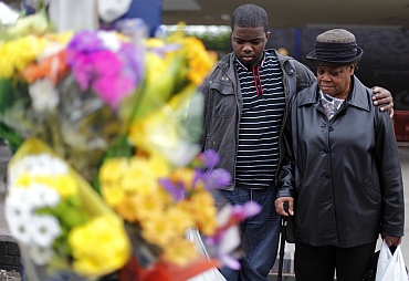 A man comforts a woman as she looks at floral tributes for three men killed by a car during the recent rioting in the Winson Green area of Birmingham