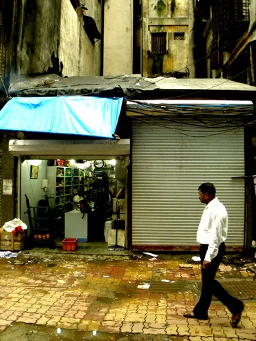 A passer-by walks past ground zero in Zaveri Bazaar. The shop with the shutter down was where the blast took place