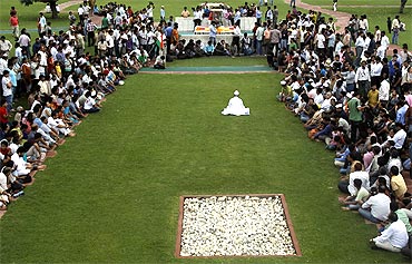 Anna Hazare, surrounded by his supporters, prays at Rajghat