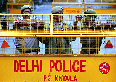 Policemen stand guard behind a barricade at the site of Hazare's proposed fast