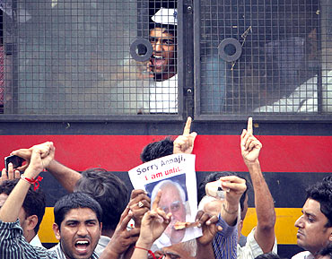 A supporter of Hazare shouts anti-government slogans from a police vehicle after being detained during a protest rally