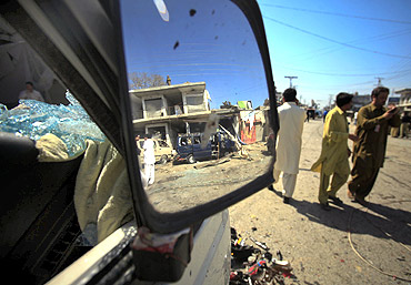 The site of a suicide bomb blast is reflected in the side mirror of a damaged vehicle in Charsadda, northwest Pakistan