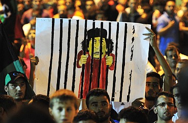 Men hold a cartoon of Gaddafi in Benghazi to celebrate the entry of rebel fighters into Tripoli. Jubilant rebel fighters streamed into the heart of Tripoli as Gaddafi's forces collapsed and crowds took to the streets to celebrate, tearing down posters of the Libyan leader