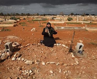 The mother of Salem Al-Moqlah, a Libyan who was killed in the clashes, reacts next to his grave in a cemetery in Benghazi February 26