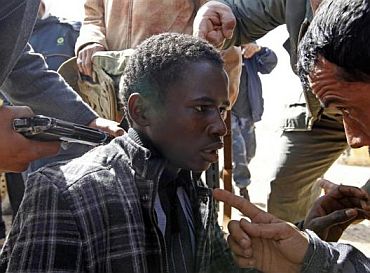 Rebels hold a young man at gunpoint, who they accuse of being a loyalist to Libyan leader Muammar Gaddafi, between the towns of Brega and Ras Lanuf, March 3