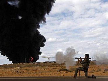 A rebel fighter fires a rocket-propelled grenade launcher in front of a gas storage terminal during a battle on the road between Ras Lanuf and Bin Jiwad, March 9