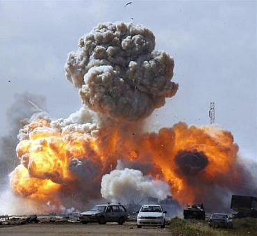 Vehicles belonging to forces loyal to Libyan leader Muammar Gaddafi explode after an air strike by coalition forces, along a road between Benghazi and Ajdabiyah March 20