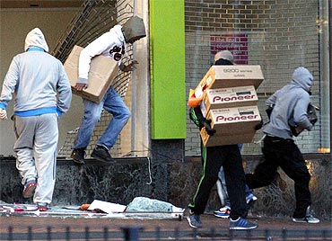 Looters carry boxes out of a home cinema shop in central Birmingham during the riots