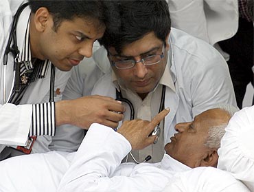 Anna Hazare speaks to doctors as they examine him at Ramlila Ground in New Delhi